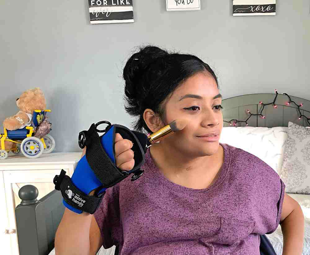 Brenda does her foundation with a large brush held in the small item aid