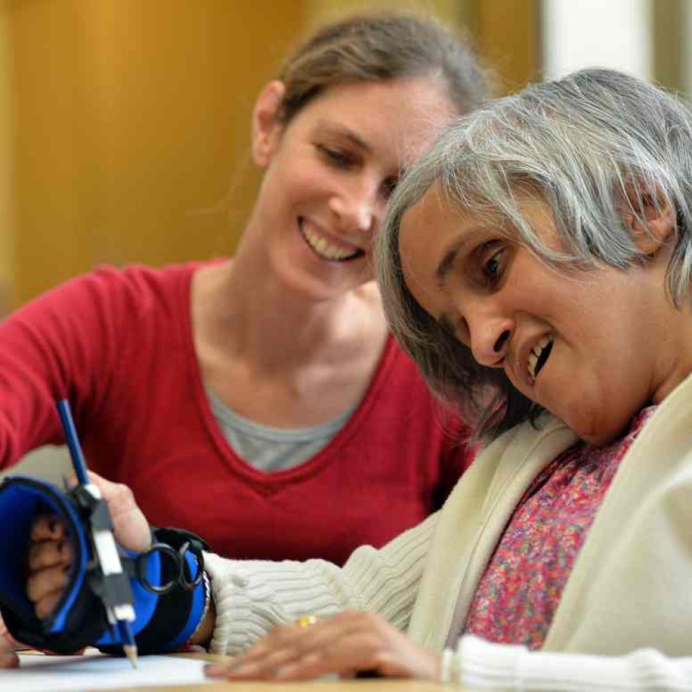 Small Item aid woman writing. Suitable for reduced hand function: tetra, quad, cerebral palsy, SCI, spinal cord injury, stroke and more.