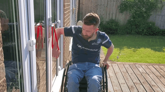 Gareth uses a red theraband to do one arm push downs