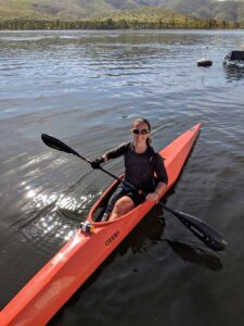 Jillian in her red kayak using a general purpose gripping aid to hold the paddle